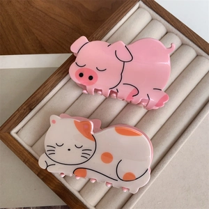 Detailed close-up of cute pink pig and cat patterned acrylic hair claws in a gift box