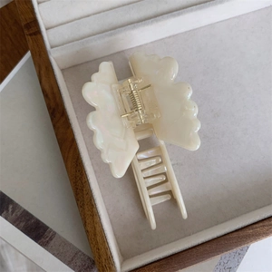 Detailed view of an acetate butterfly hair claw clip with pearl luster in a jewelry box