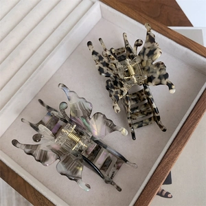 Détail de pinces à cheveux papillon aux motifs écaille et gris fumé sur plateau en bois