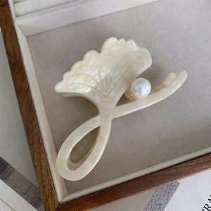 Detailed shot of ginkgo leaf hair claw clip with pearl on cream velvet jewelry box