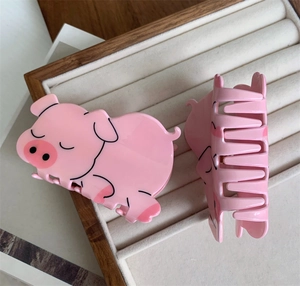 Detail view of cute pink pig acrylic hair claw clip with smooth glossy finish and sturdy teeth