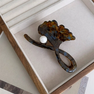 Detail of a ginkgo leaf hair claw clip with tortoise shell pattern and a white pearl accent