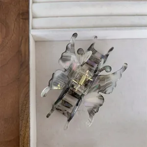 Détail d'une pince à cheveux papillon 3D avec texture marbre irisé et ressort doré