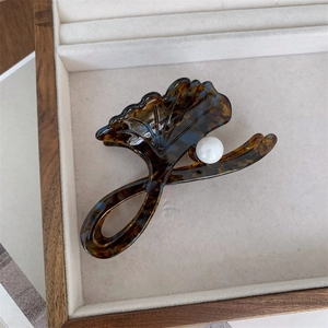 Close-up of tortoise shell ginkgo leaf hair claw with white pearl on velvet tray
