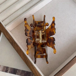 Vue détaillée de la pince à cheveux papillon avec motif écaille et ressort doré