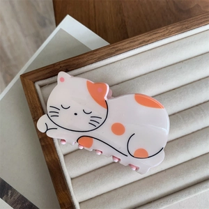Detailed view of a cute sleeping cat hair claw clip made of glossy cream acrylic material