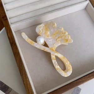 Detail of ginkgo leaf hair claw clip with pearl accent and amber marble texture