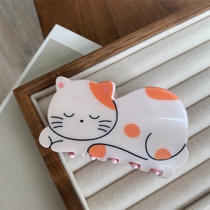 Close-up of cute sleeping cat hair claw clip made of acrylic in a velvet display box