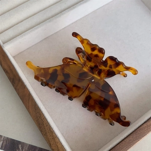 Vue détaillée d'une pince à cheveux papillon avec texture écaille de tortue dans un plateau