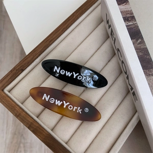 Détail de barrettes ovales noires et écaille avec texte NewYork sur plateau en velours