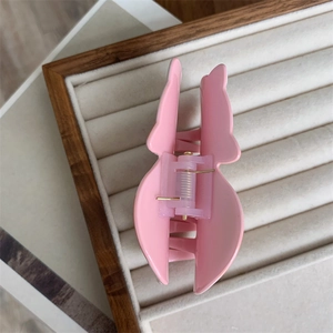 Detail of pink butterfly hair claw clip with metallic spring mechanism on jewelry tray