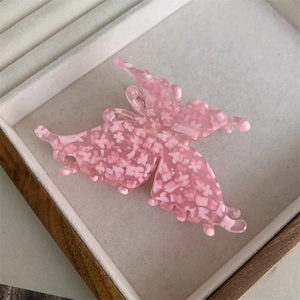 Détail de la pince à cheveux papillon rose avec des motifs floraux blancs fins