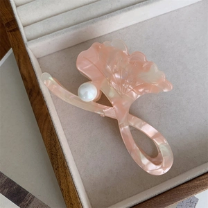 Detail of pink marble acetate hair claw in ginkgo leaf shape with pearl accent