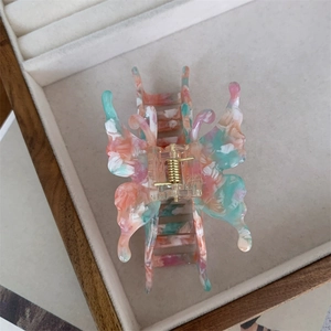 Détail d'une pince à cheveux papillon rétro en acétate marbré dans une boîte à bijoux