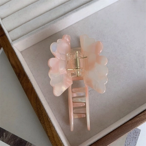 Detail view of pink marble acetate butterfly hair claw clip with golden metal spring