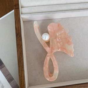Detailed macro view of pink marble acetate hair claw with central pearl decoration