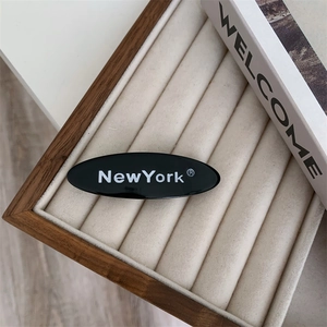 Vue détaillée d'une barrette ovale noire avec texte NewYork dans un coffret en velours