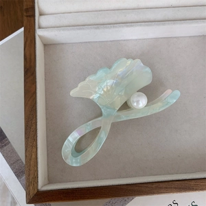 Detailed macro view of mint green acetate ginkgo hair claw clip with a white pearl accent