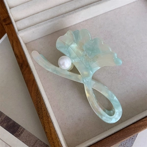 Macro detail of ginkgo leaf hair claw clip with pearl on a velvet jewelry display box