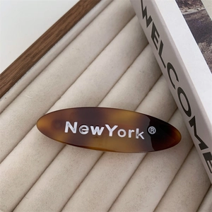 Barrette ovale écaille de tortue avec texte New York blanc sur un support élégant