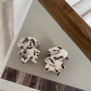 Détail de deux pinces à cheveux ours avec motif marbré noir et blanc sur un plateau gris