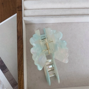 Detail of blue and pearl acetate hair claw clip with golden spring on felt display tray