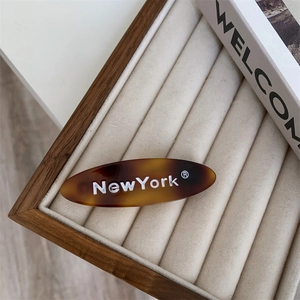 Détail d'une barrette ovale en acétate écaille de tortue avec texte blanc New York