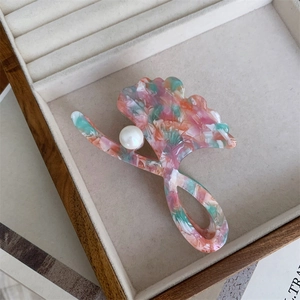 Close-up of acetic acid floral hair claw with pearl detail in a velvet jewelry box