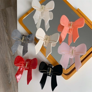 Elegant acetate bow hair claws in seven colors displayed on a decorative mirror stand