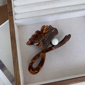 Detail of tortoise shell claw clip with ginkgo leaf design and pearl in a jewelry box