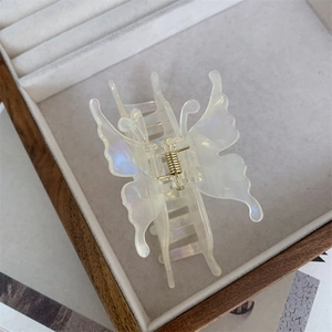 Gros plan d'une pince à cheveux papillon 3D nacrée avec un ressort en métal doré