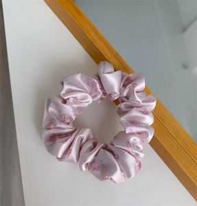 Close-up of pink floral scrunchie with soft silk texture and delicate flower pattern