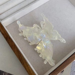 Détail macro d'une pince à cheveux papillon rétro française blanc perle aurore