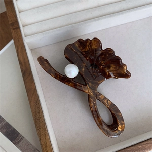Detailed view of amber marble ginkgo leaf hair claw clip with a white pearl accent