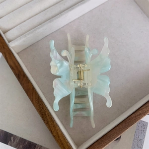 Détail de la pince à cheveux papillon en acétate marbré bleu dans un coffret à bijoux