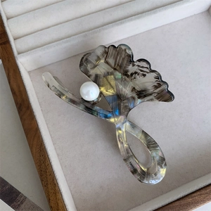 Detail of acetate ginkgo leaf hair claw with iridescent finish and pearl accent