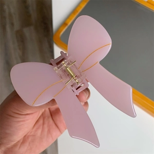 Detailed macro view of pink bow acetate hair claw clip showing glossy material and spring