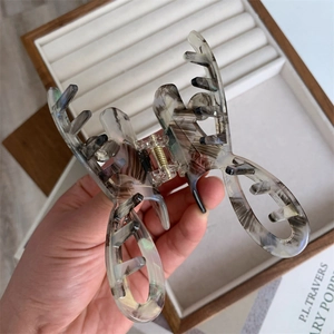 Detail view of large marbled acetate hair claw clip with golden metal spring