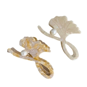 Elegant ginkgo leaf hair claws in cream and amber acetate with pearls on white background