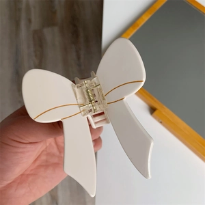 Close-up of a white acetate butterfly hair claw clip with golden edges and metal spring