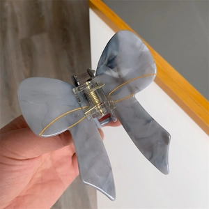 Detail of grey marble acetate butterfly hair claw clip with golden metal spring
