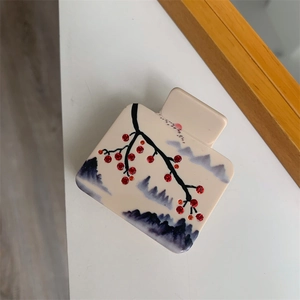 Détail du motif de peinture à l'encre et des strass étincelants sur la pince à cheveux