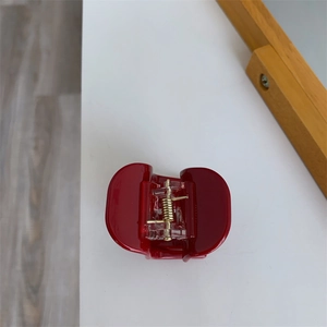 Close-up of a glossy red acetate hair claw clip with a strong golden metal spring