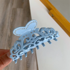 Detail of light blue acetic acid hair claw with hollow carved heart and tiny rhinestones