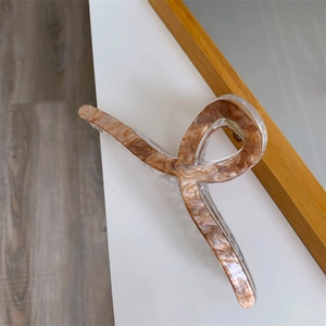Detail view of a 13cm double-layered acrylic hair claw with amber marble pattern