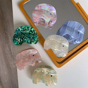 Detail view of various marble-patterned elephant hair claws on a mirrored surface