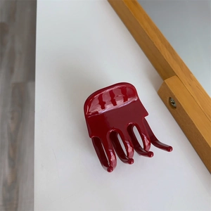 Detailed macro view of dark red acetate hair claw clip with octopus-style gripping teeth