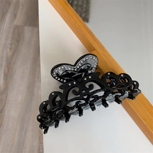 Close-up of black hollow-out acetate hair claw with rhinestones and heart patterns