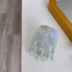 Close-up of marble grey-blue acetate hair claw clip with pearlescent texture and glossy finish