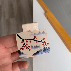Gros plan d'une pince à cheveux carrée en acétate avec motif de paysage chinois et strass